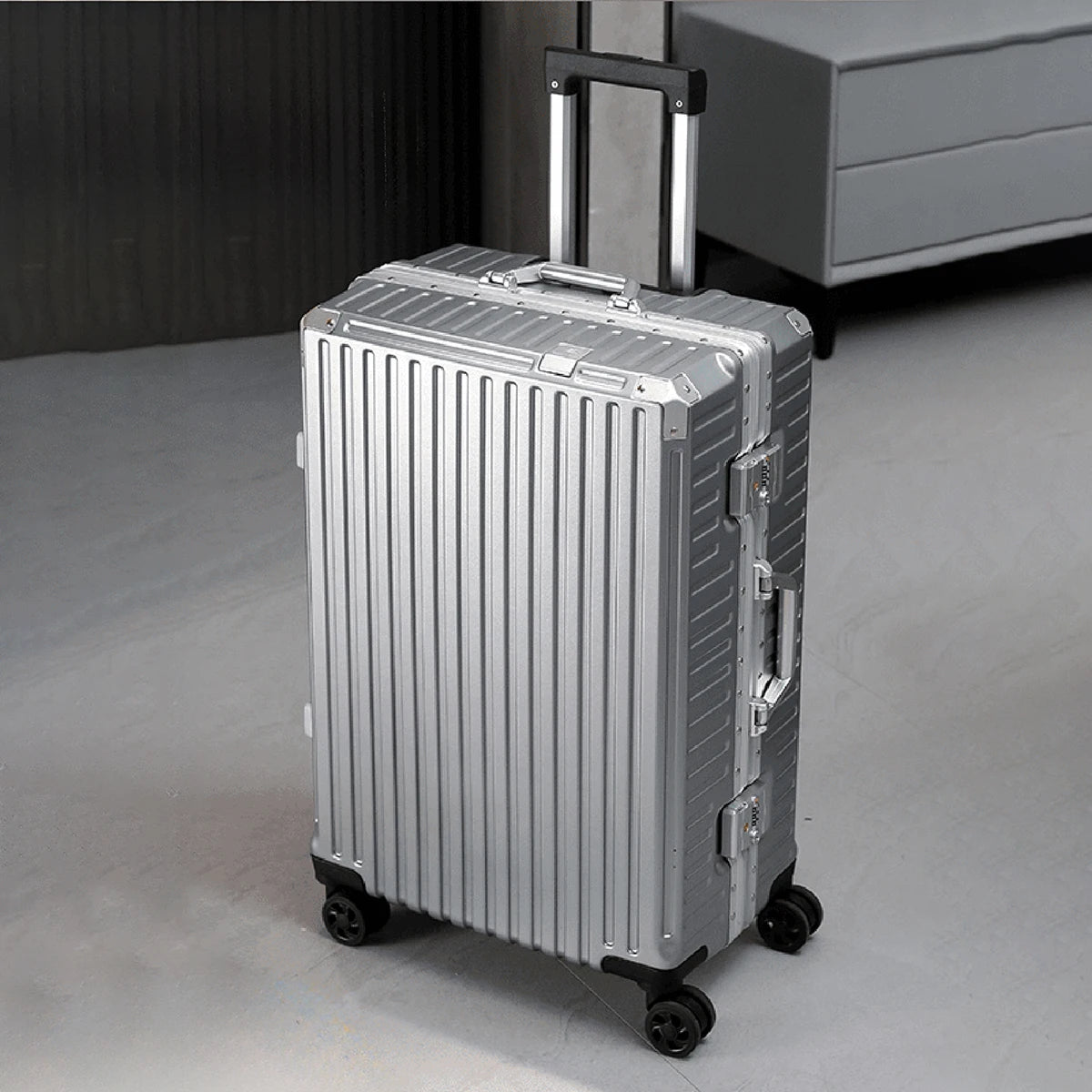 Silver suitcase with black wheels on a gray floor