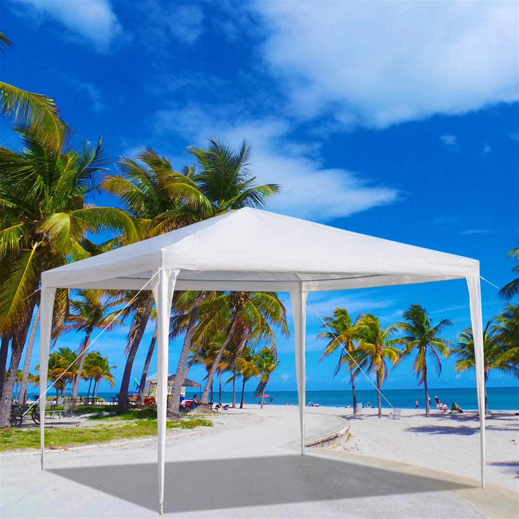 White outdoor canopy tent on a beach with palm trees and blue sky.