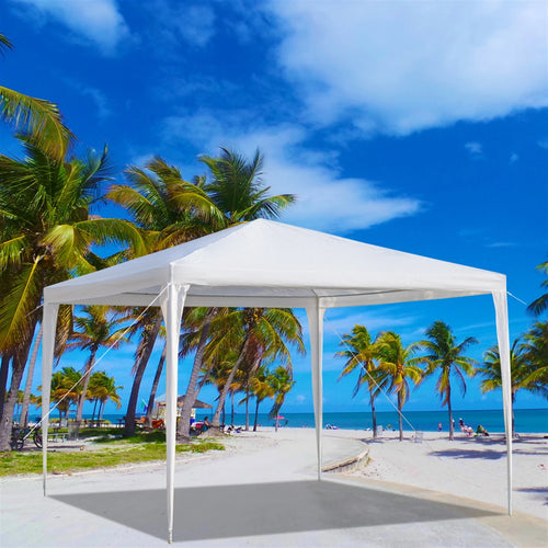 White outdoor canopy tent on a beach with palm trees and blue sky.