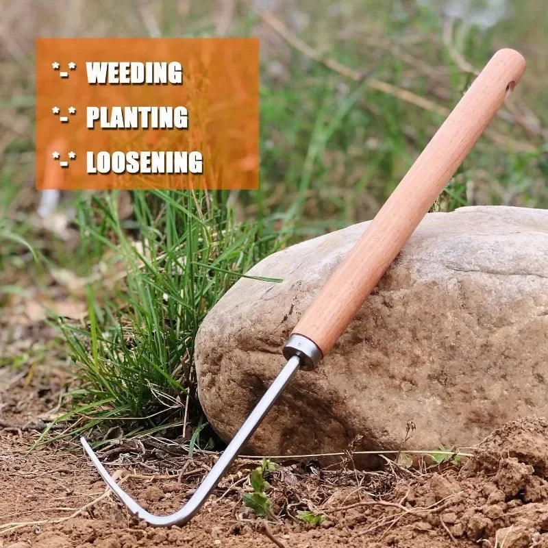 Gardening tool with wooden handle and metal blade leaning against a rock with grass in the background.