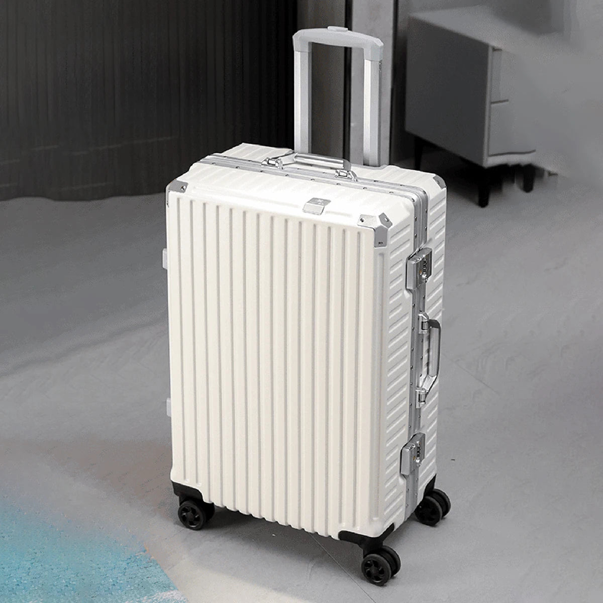 White suitcase with silver accents on a gray floor